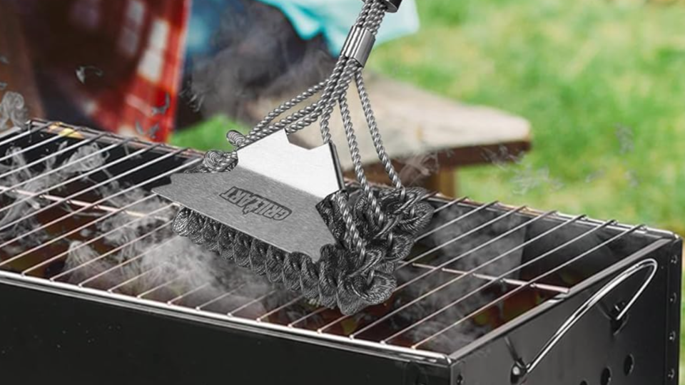 bristle-free grill brush being used on vertical grill grates