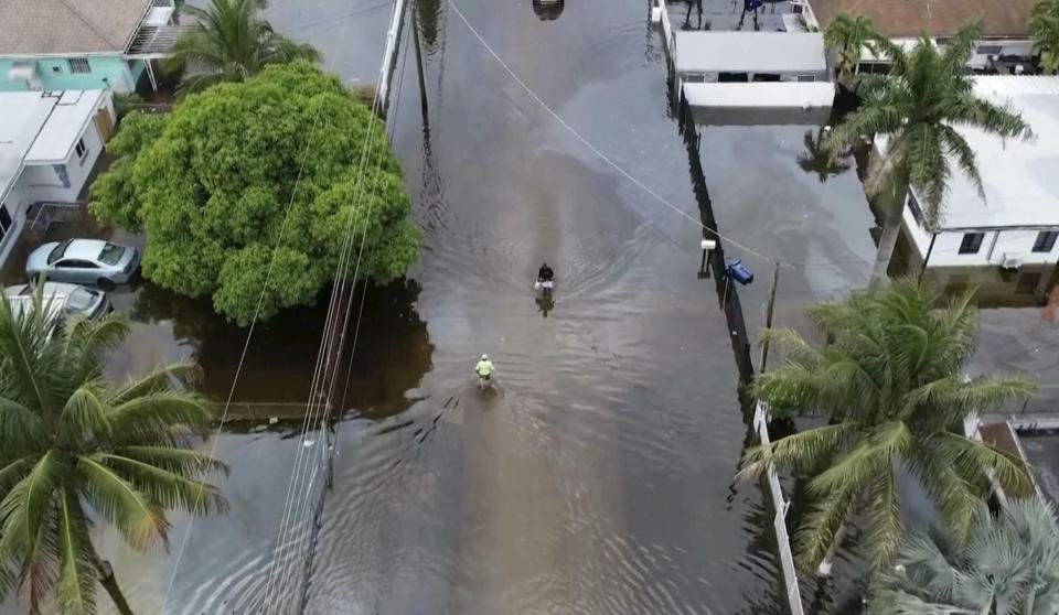 An aerial view of two people walking on a flooded street.