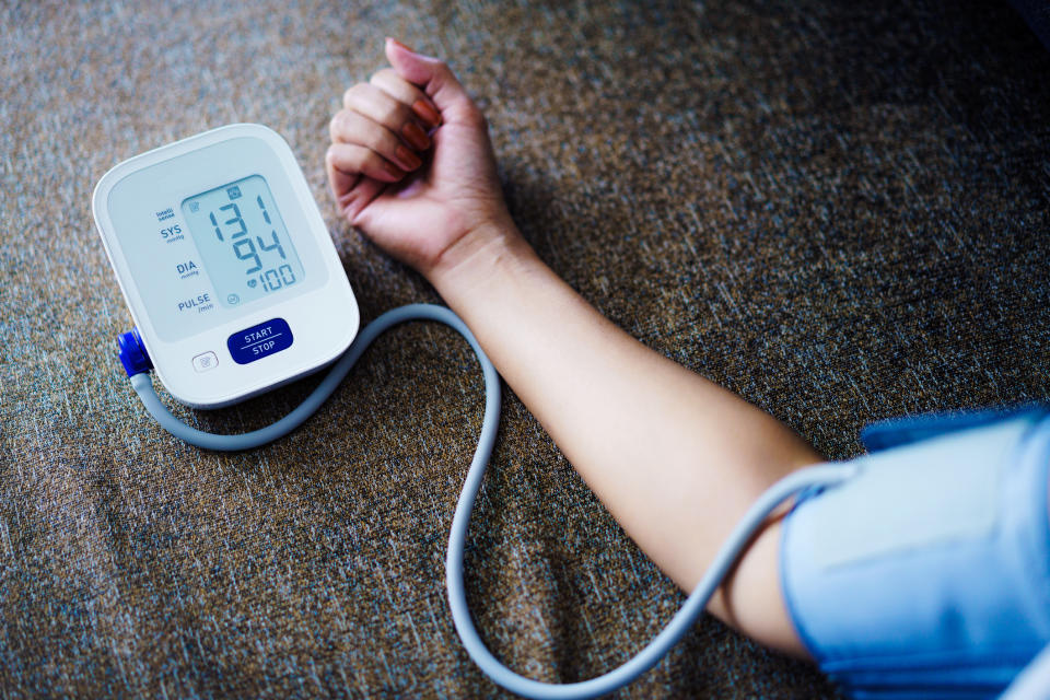 Close-up of a person's arm with a blood pressure cuff, displaying the reading of 131/94 mmHg and a pulse rate of 100 on the monitor