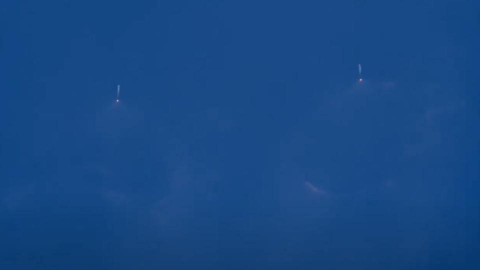 a large white rocket launches through a clear blue sky