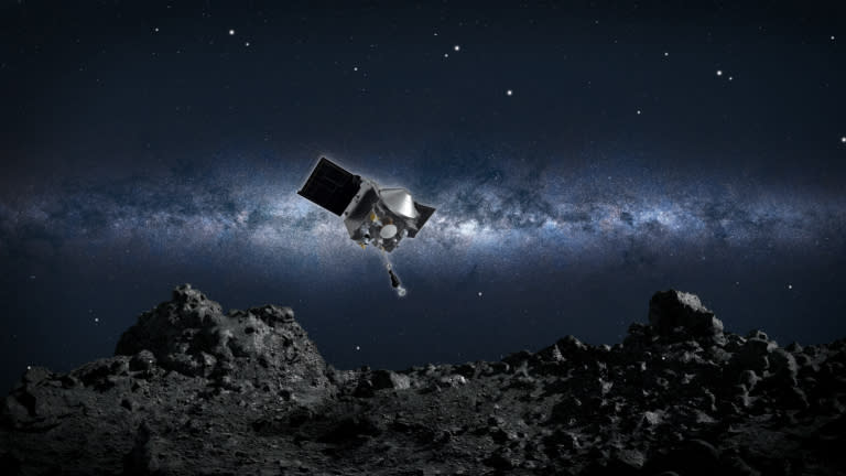 A spacecraft is seen in space above a dark and rocky ground.