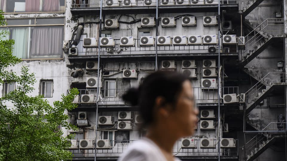 A woman walks past air-conditioning units outside a building in Seoul on April 30, 2024. - Anthony Wallace/AFP/Getty Images