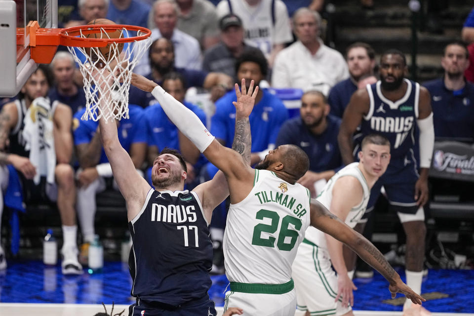 Dallas Mavericks guard Luka Doncic, left, goes up for a basket against Boston Celtics forward Xavier Tillman during the first half in Game 3 of the NBA basketball finals, Wednesday, June 12, 2024, in Dallas. (AP Photo/Tony Gutierrez)