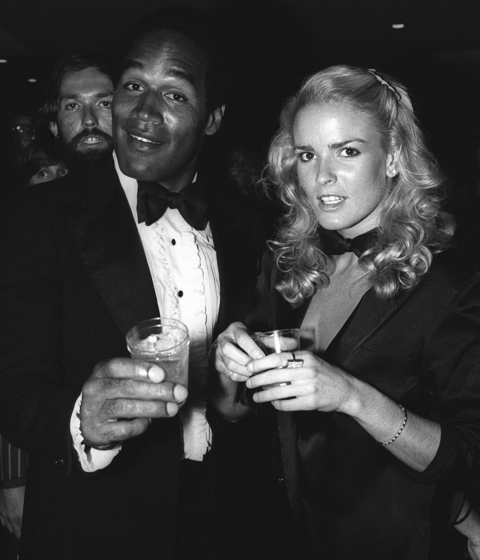 O.J. Simpson and Nicole Brown Simpson shown together holding drinks.