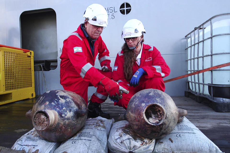 This photo released by Israel's Antiques Authority (IAA) on June 20, 2024 shows Jacob Sharvit, left, and Dr. Karnit Bahartan, right, with the ancient jars that were carried on the world's oldest known deep-sea shipwreck, discovered some 55.9 miles off the Israeli coastline. / Credit: Emil Aladjem/Israel Antiquities Authority/AP