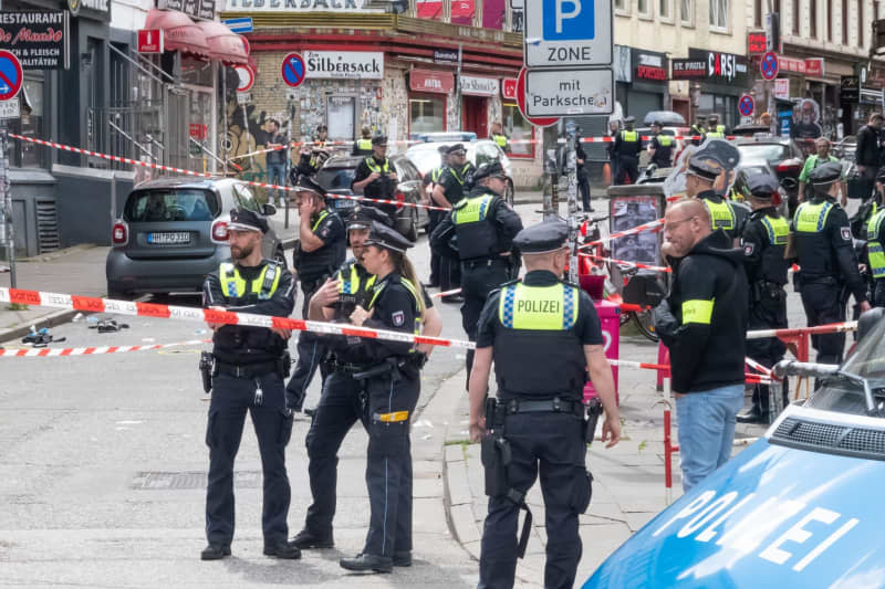 Police officers stand at the scene. Police have shot a man armed with a pickaxe and a Molotov cocktail near the Reeperbahn in Hamburg-St. Pauli. He was hit in the leg and is receiving medical treatment, a police spokesman said on Sunday. Bodo Marks/dpa