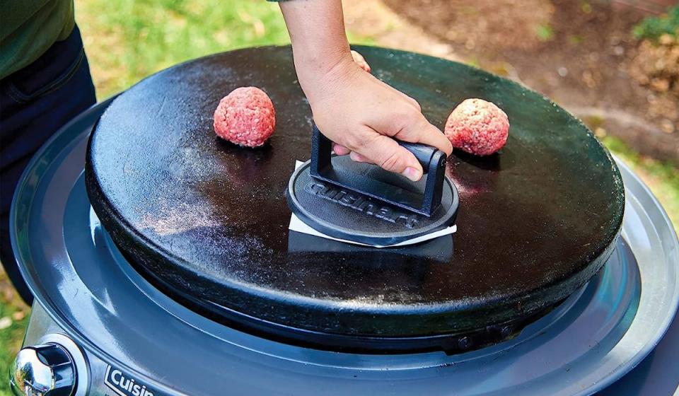 Man using burger press on griddle.