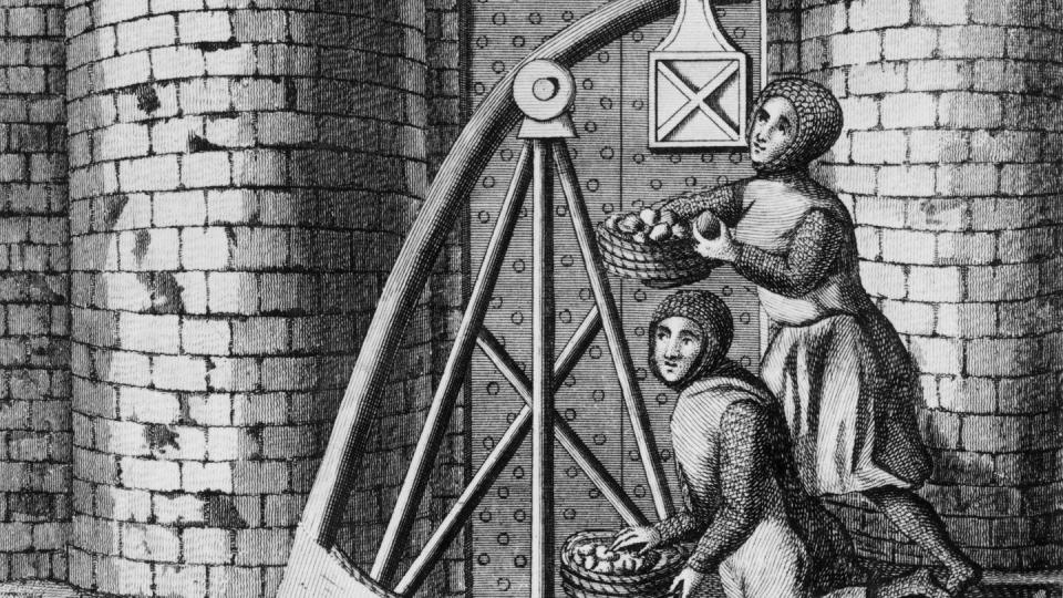 Circa 1400, soldiers wearing chain mail load baskets of stones onto a trebuchet behind the walls of a castle. (Hulton Archive/Getty Images)