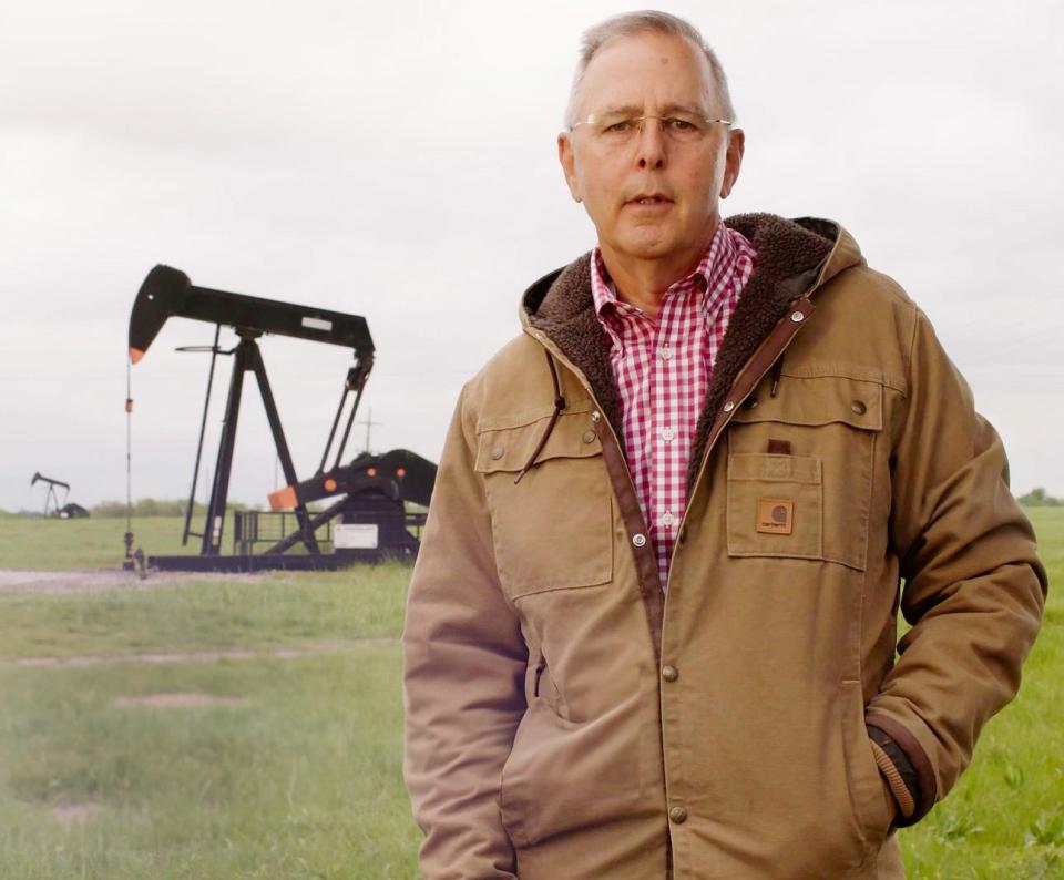 Brian Bingman stands in front of an oil well. Bingham is running for Corporation Commissioner.