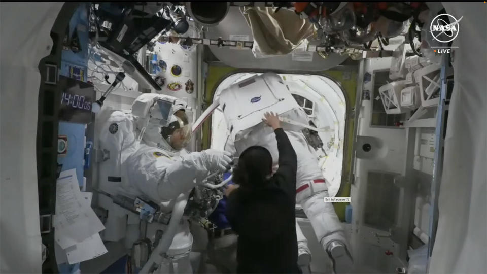 Astronaut Tracy Dyson, wearing a spacesuit with red stripes, is helped back into the spacewalk staging compartment after a coolant leak prompted flight controllers to call off a planned 6.5-hour spacewalk. Crewmate Michael Barratt can be seen at left as both were assisted by station astronauts Jeanette Epps (in dark shirt) and Matthew Dominick (out of sight behind the others). / Credit: NASA