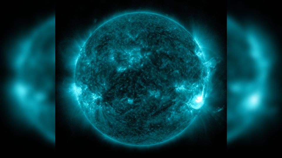 a green false-color image of the sun shows a large plume of white light exploding out of its southeastern edge
