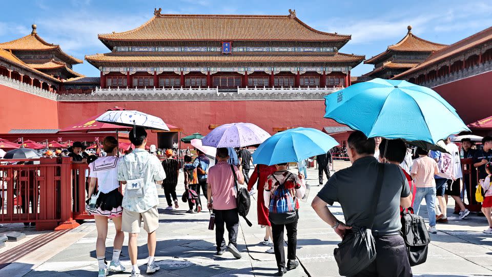 Tourists shield themselves from the sunshine while visiting the Palace Museum during the Dragon Boat Festival holiday on June 9, 2024 in Beijing, China. Beijing Meteorological Observatory issued the first yellow alert for high temperatures in 2024, with the highest temperature in the city reaching 35 degrees Celsius. - VCG/Getty Images