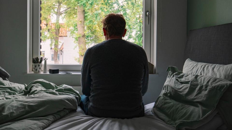 PHOTO: In this undated stock photo, a man is seen sitting alone on his bed as he looks out a window. (STOCK PHOTO/Getty Images)