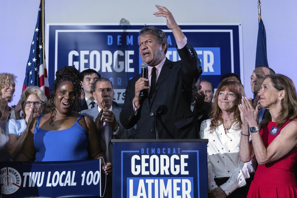 George Latimer at podium surrounded by a dozen people.