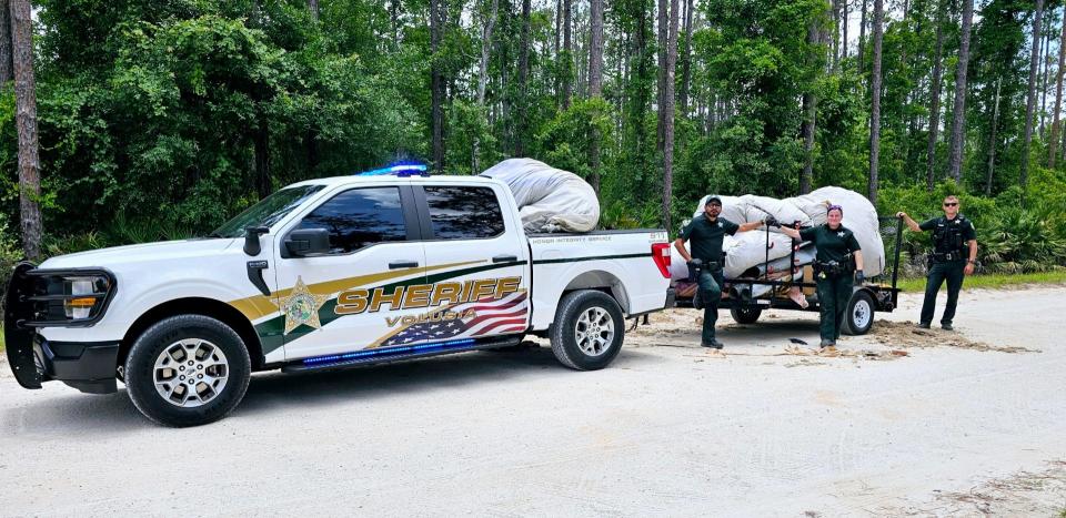 Volusia County Sheriff's Office deputies haul away some 860 pounds of trash dumped in the middle of 9 Mile Point Road near the Lake George Wildlife Management Area in Pierson on June 2.