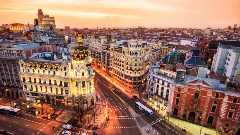 Aerial view of Gran Via in Madrid at dusk from Circulo de Bellas artes. the sky is orange.