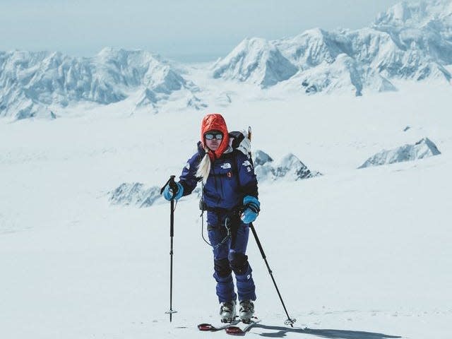 A woman on skis with snowy peaks in the background