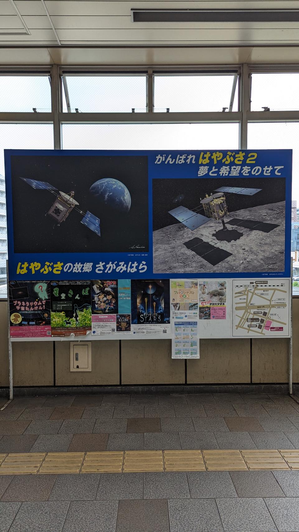 A posterboard in front of several windows with lots of posters and papers that have space images and mission promotional art on them.