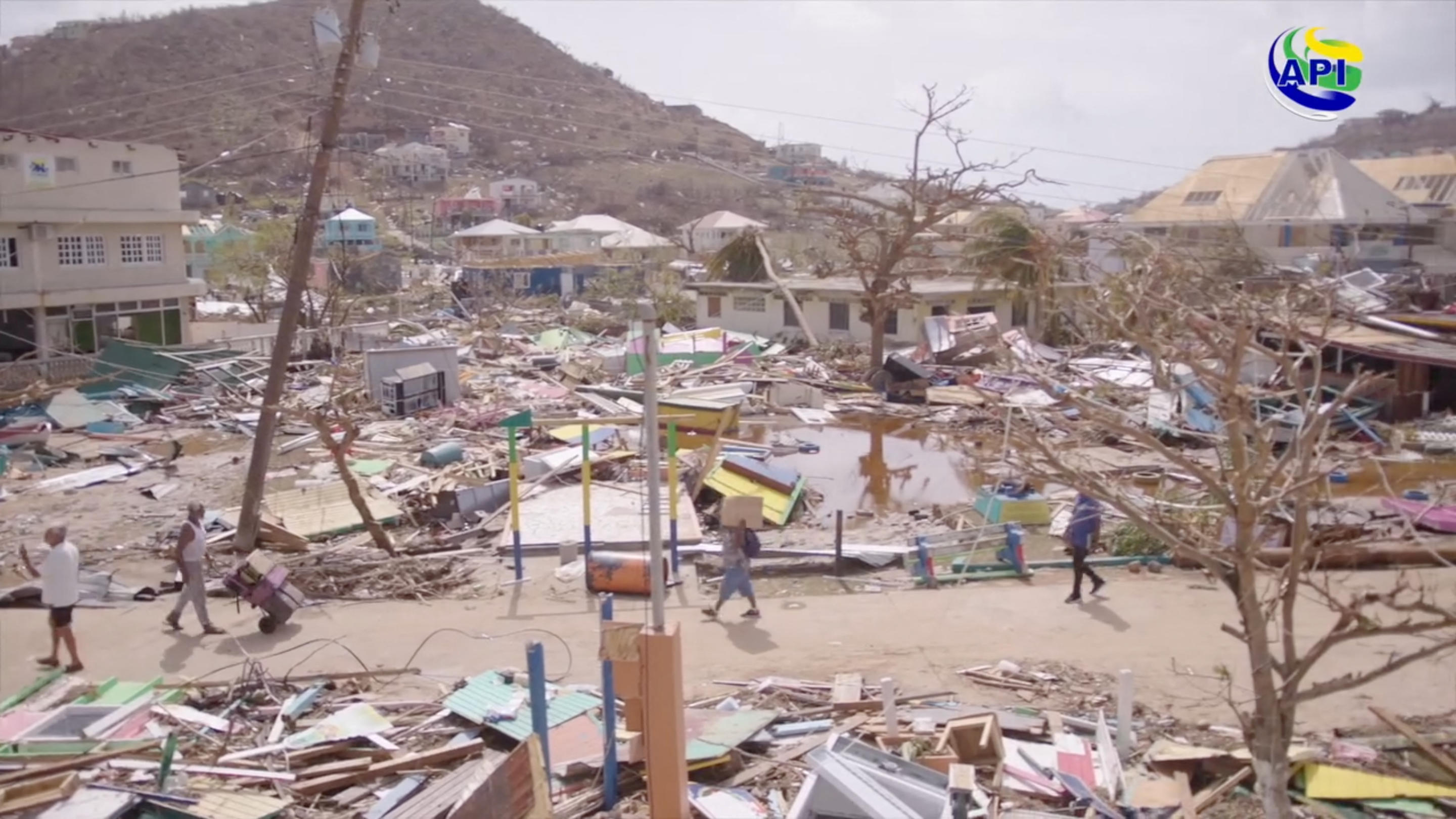 People walk by property damaged by Hurricane Beryl in Union Island, St. Vincent and the Grenadines.