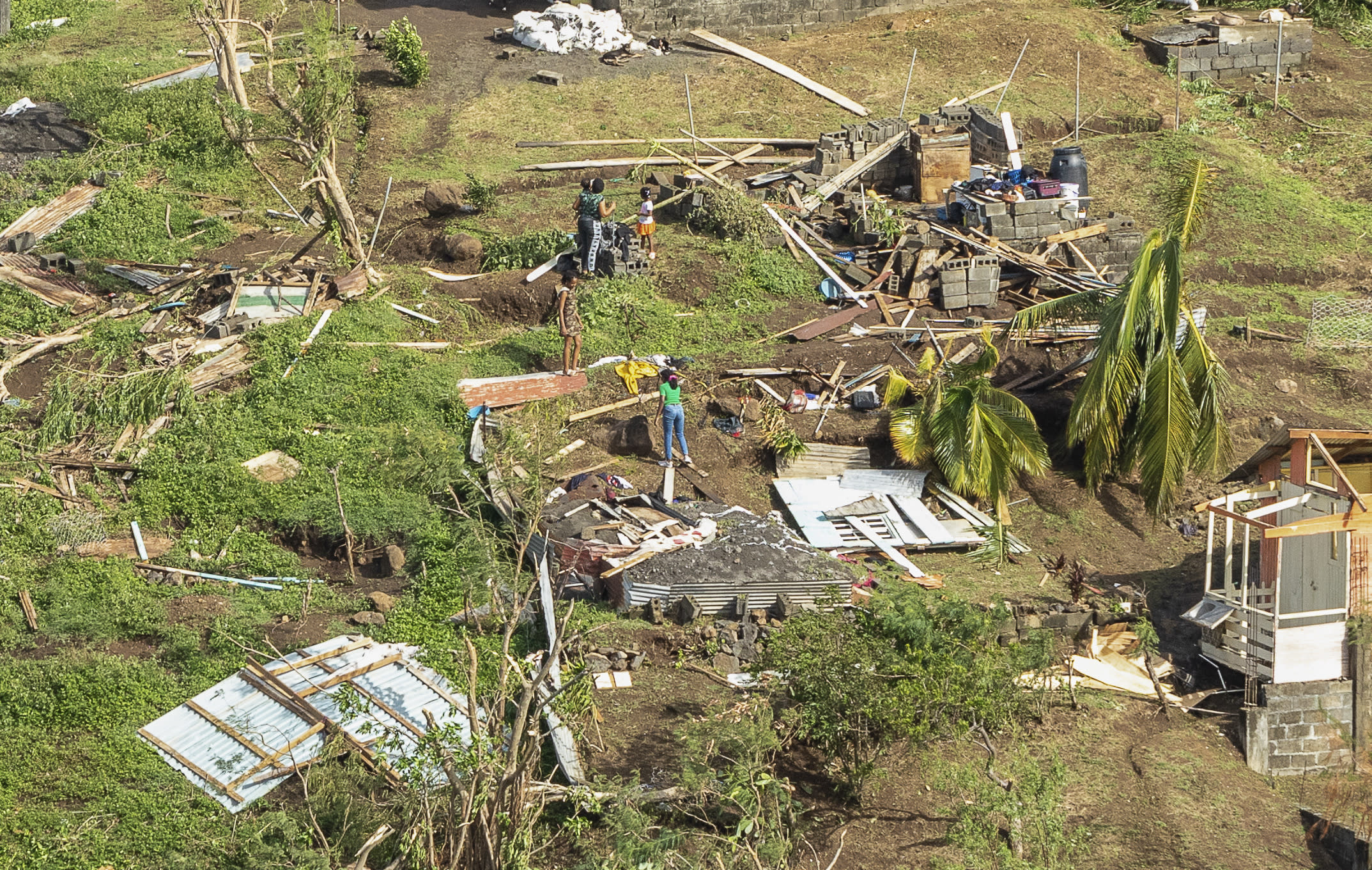 People survey the damage to a home destroyed by Hurricane Beryl in Ottley Hall, St. Vincent and the Grenadines. 