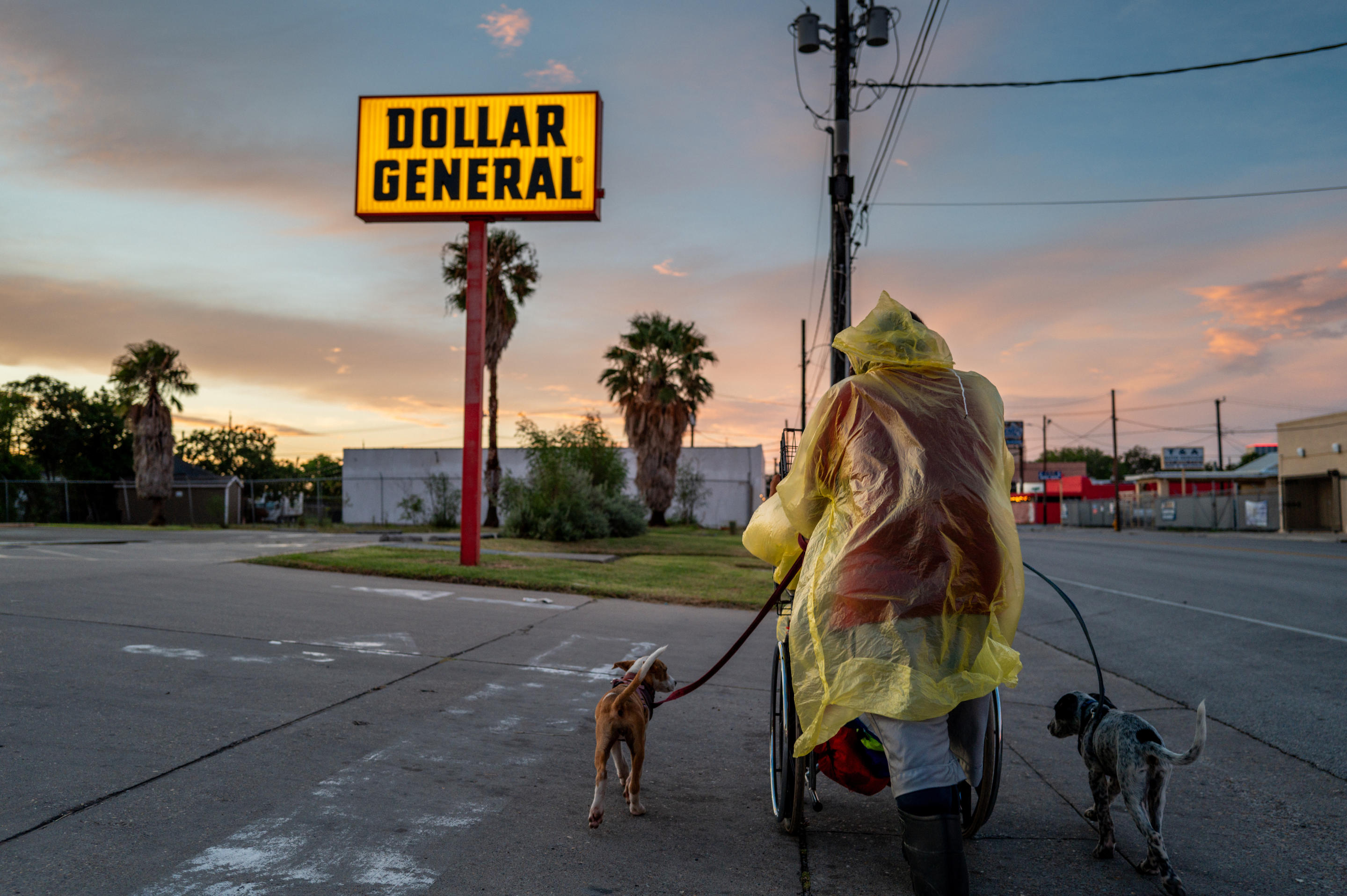 A homeless couple, one in a wheelchair, with two dogs, near a Dollar General store prepare to seek shelter ahead of Tropical Storm Beryl's arrival on July 7, in Corpus Christi, Texas