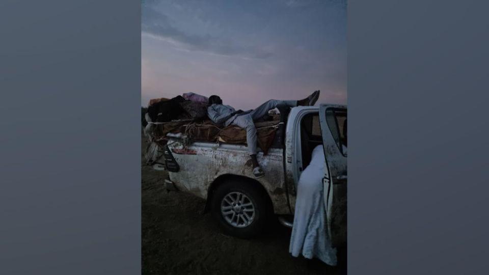 A person resting on the back of a pick up truck