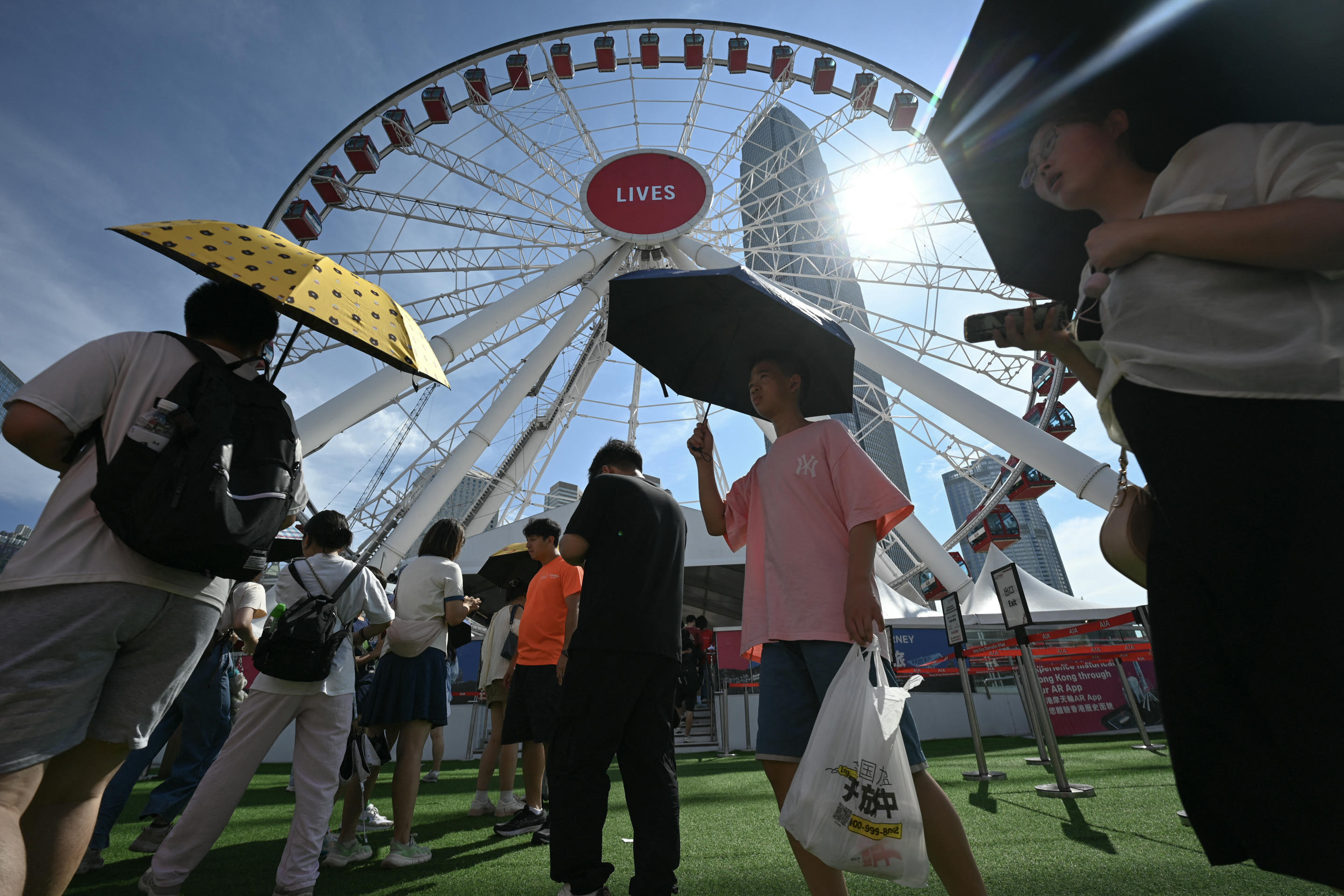 Tourists use umbrellas to protect themselves from the sun.