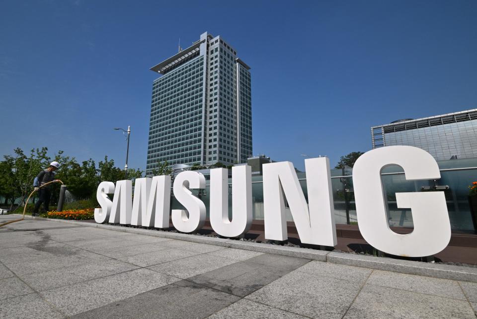 A worker waters the flower garden next to the logo of Samsung Electronics at the company's headquarters in Suwon on June 13, 2023. (Photo by Jung Yeon-je / AFP) (Photo by JUNG YEON-JE/AFP via Getty Images)