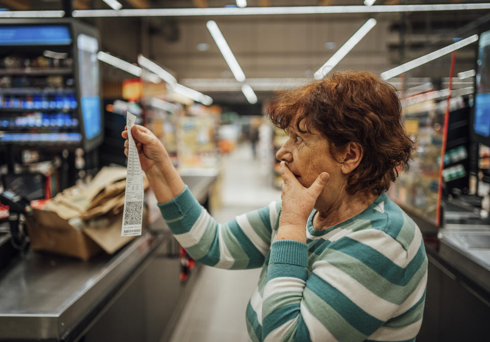 Senior woman feeling shocked because of the high amount on the bill in the supermarket