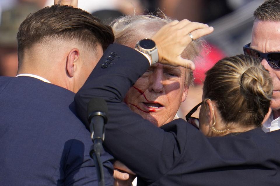 Republican presidential candidate former President Donald Trump is helped off the stage by U.S. Secret Service agents at a campaign event in Butler, Pa., on Saturday, July 13, 2024. (AP Photo/Gene J. Puskar)