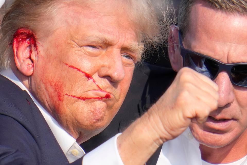 Republican presidential candidate former President Donald Trump gestures as he is surrounded by U.S. Secret Service agents as he is helped off the stage at a campaign rally in Butler, Pa., Saturday, July 13, 2024. (AP Photo/Gene J. Puskar)