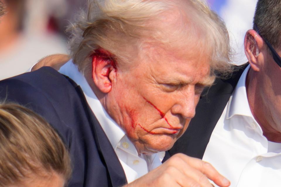 Republican presidential candidate former President Donald Trump is surrounded by U.S. Secret Service agents as he is helped off the stage at a campaign rally in Butler, Pa., Saturday, July 13, 2024. (AP Photo/Gene J. Puskar)