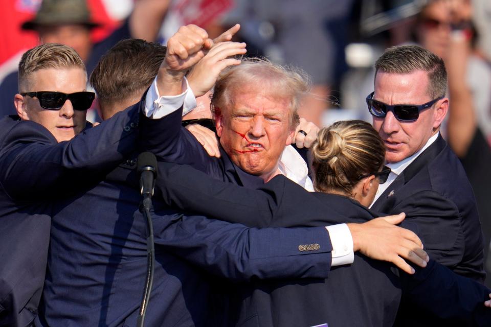 Republican presidential candidate former President Donald Trump pumps his fist as he is helped off the stage at a campaign event in Butler, Pa., on Saturday, July 13, 2024. (AP Photo/Gene J. Puskar)