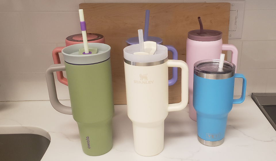 Six handled water tumblers are lined up for testing, including Owala, Stanley and Yeti brands.