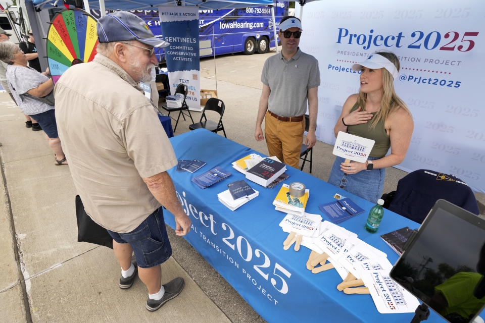 Kristen Eichamer, right, and Spencer Chretien, center, talk to Russ Pinta, left, of Colo, Iowa, at the Project 2025 tent at the Iowa State Fair, Aug. 14, 2023, in Des Moines, Iowa. With more than a year to go before the 2024 election, a constellation of conservative organizations is preparing for a possible second White House term for Donald Trump. The Project 2025 effort is being led by the Heritage Foundation think tank. (AP Photo/Charlie Neibergall)