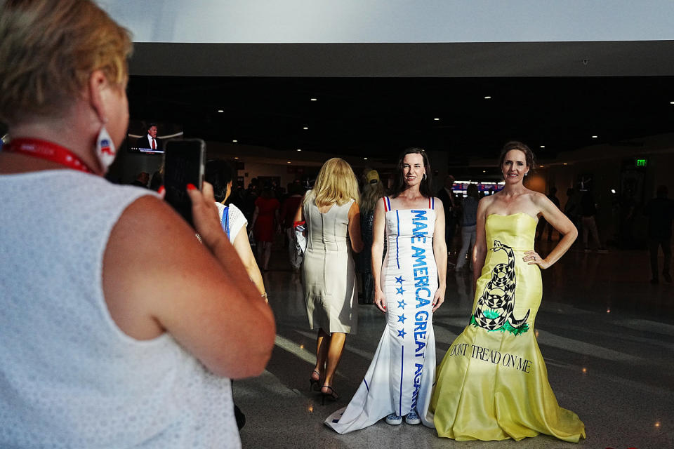 A woman takes a photo of attendees in gowns  (Hiroko Masuike / New York Times via Redux )