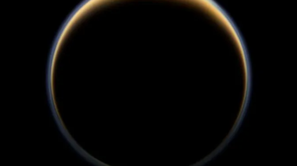 A dark sphere bounded by a brown-yellow ring that is thicker at the sphere's north pole