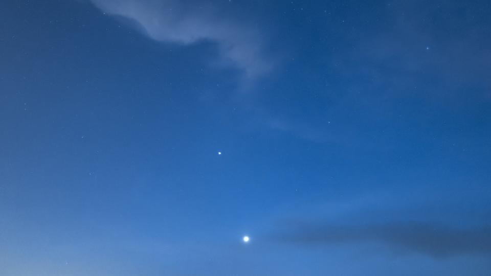 a dark blue sky with thin wispy clouds and two bright points of light one is venus and the other mercury.