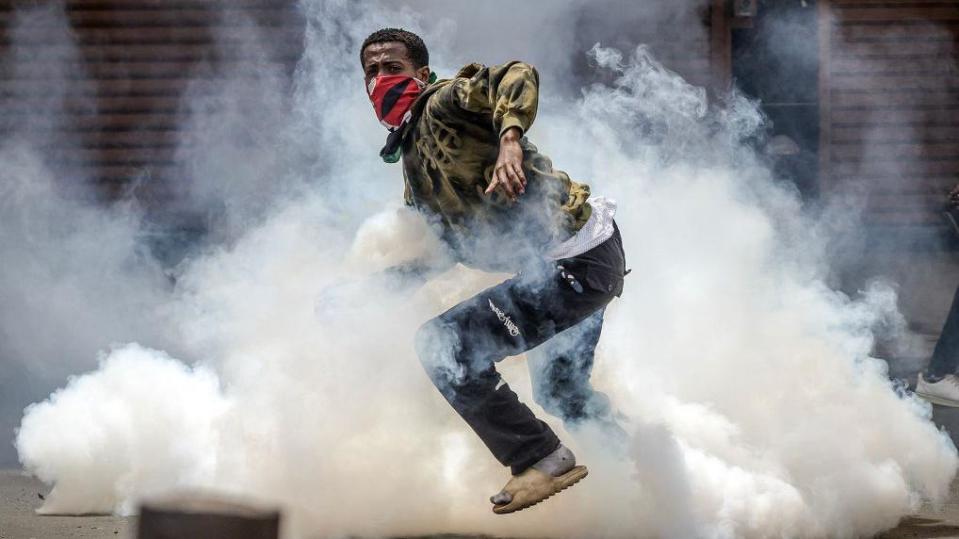 Protesters react to tear gas launched by anti-riot police during an anti-government demonstration called following nationwide deadly protests over tax hikes and a controversial now-withdrawn tax bill in downtown Nairobi, on July 2, 2024.