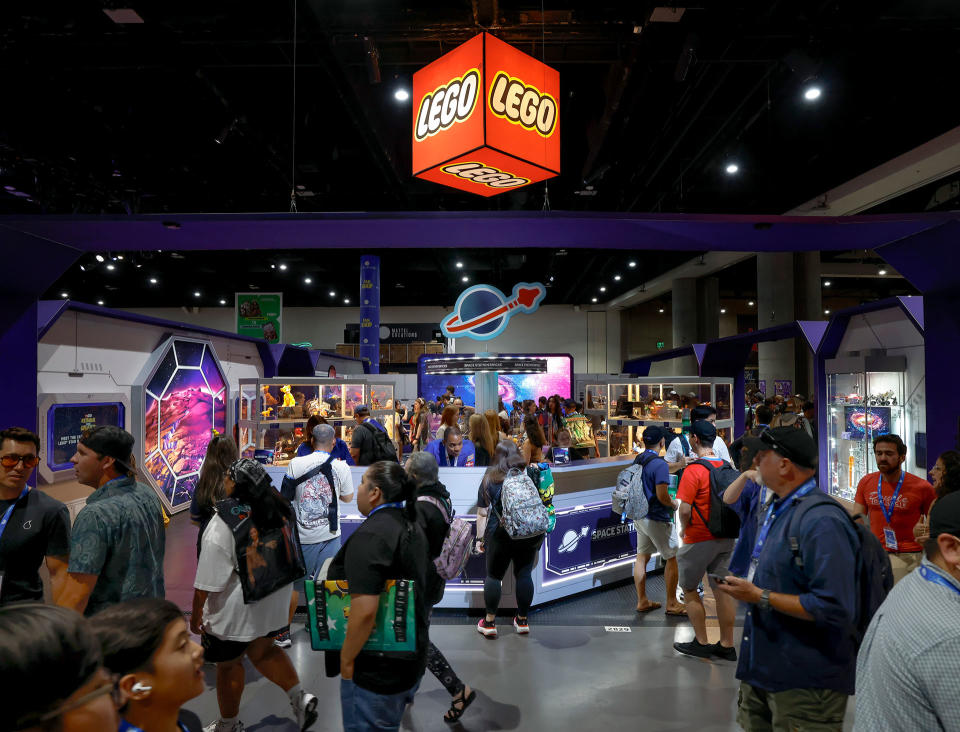 a large group of people congregate on a show floor at a comics convention. a red cube that says 