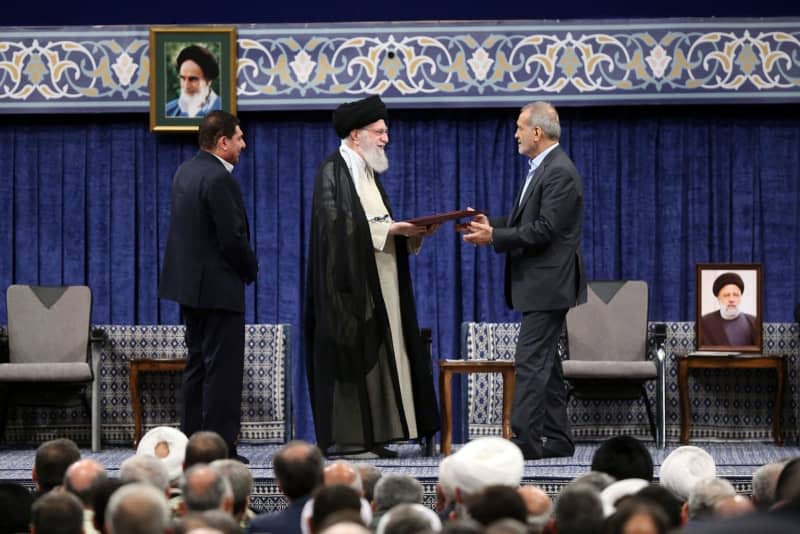 Iranian supreme leader Ayatollah Ali Khamenei (C-L) hands his seal of approval to newly-elected President Masoud Pezeshkian, during the new president endorsement ceremony in Tehran. -/Iranian Presidency/dpa