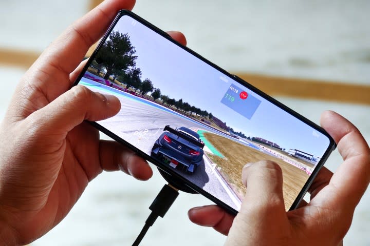 AMOLED screen with Real Racing 3 running at 120fps on the Infinix GT 20 Pro gaming phone held in hand.