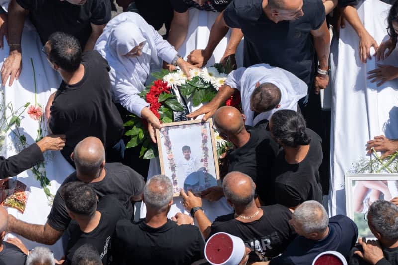 People mourn at the funeral of their relatives in the Druze town of Majd al-Shams in the Israeli-controlled Golan Heights. Several children and young people were killed in a rocket attack on a football field in the village. Ilia Yefimovich/dpa