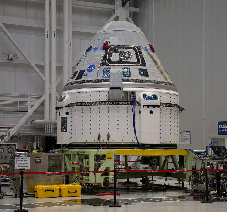 The Starliner capsule seen during pre-launch processing at a Boeing facility at the Kennedy Space Center. Problems with aft-facing thrusters and propulsion system helium leaks in the lower drum-shaped service module have delayed the crew's return to Earth. Weekend test firings indicated the thrusters will work as needed for re-entry and return to Earth. / Credit: William Harwood/CBS News