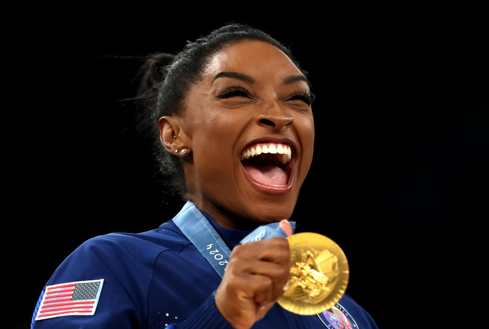 Simone Biles grins as she holds her gold medal at the 2024 Summer Olympics in Paris.