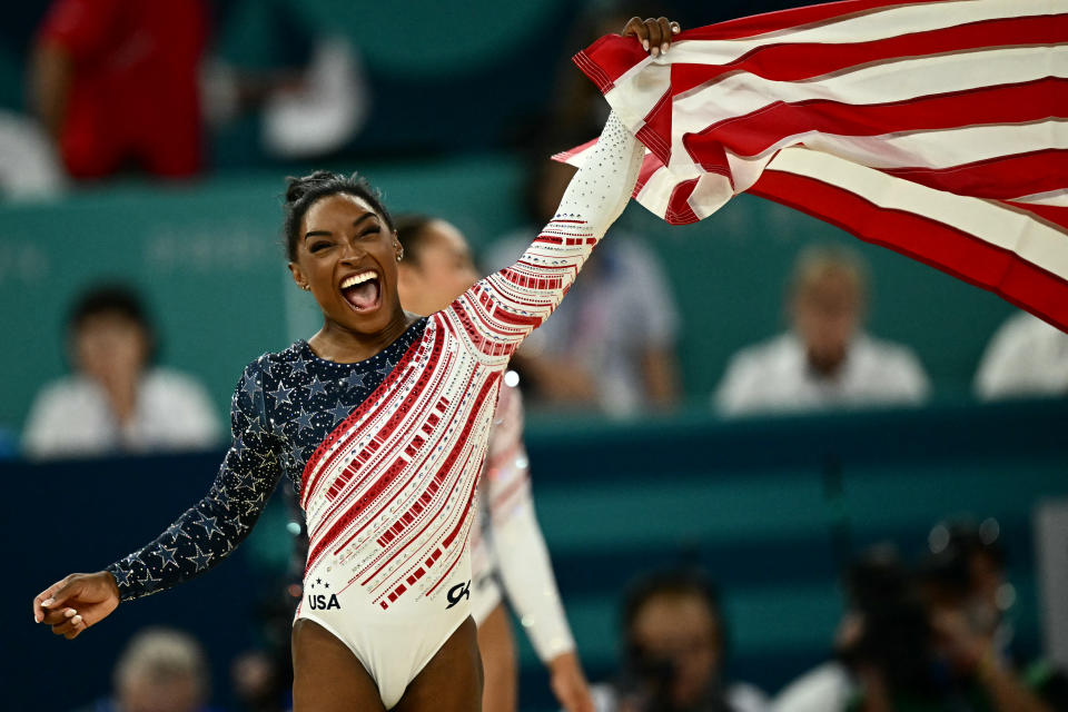 Biles waves an American flag after Team USA's win at the Paris 2024 Olympic Games.