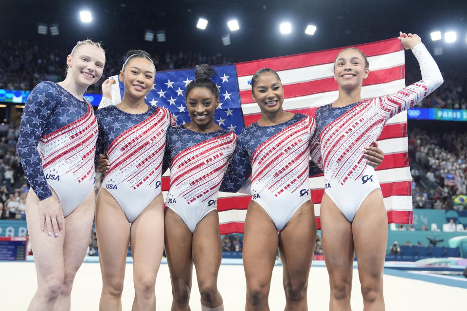 Team USA, from left to right -- Jade Carey, Suni Lee, Simone Biles, Jordan Chiles and Hezly Rivera -- celebrates gold while holding the U.S. flag. 