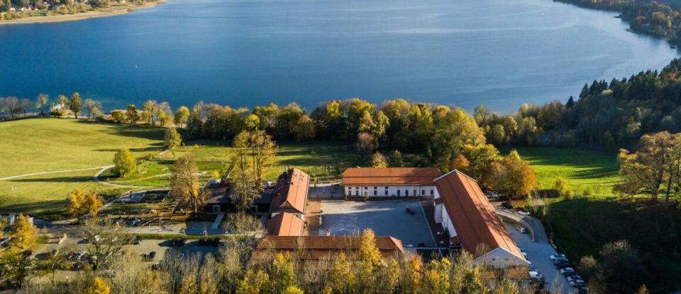 a building with a grass field and trees by a body of water