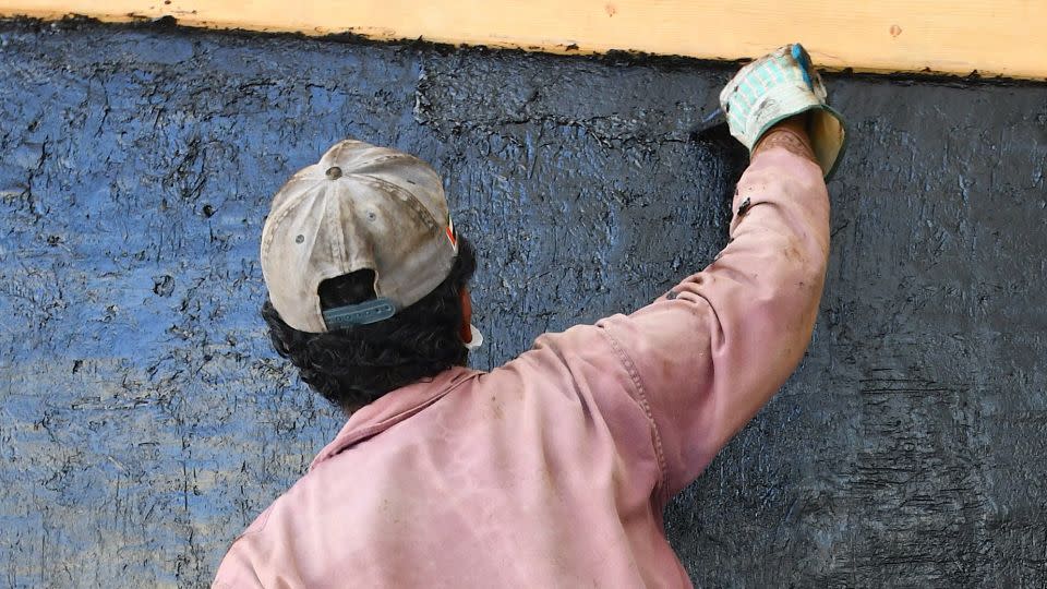 A team member helps to coat the boat with bitumen for waterproofing. - Zayed National Museum