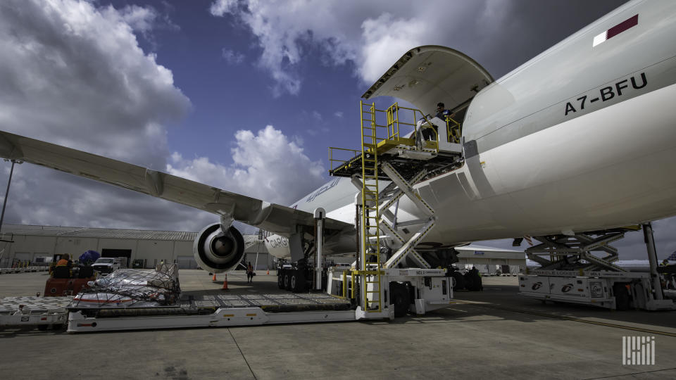 Close up of large jetliner with cargo door open, view from the tarmac behind the wing.